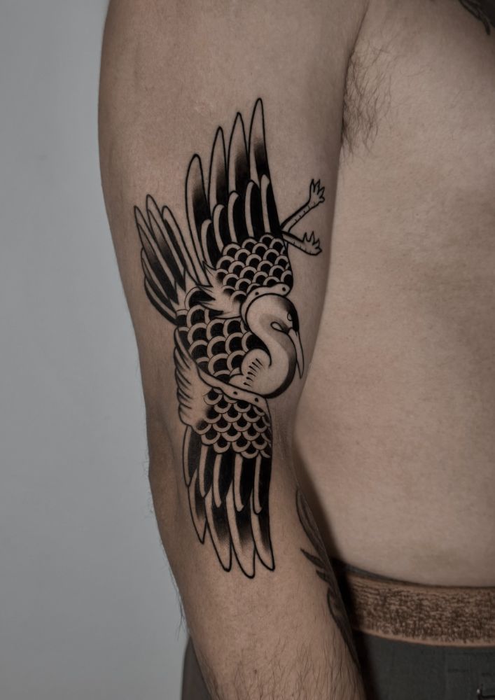 Tatuagem de grou de asas abertas, no braço.