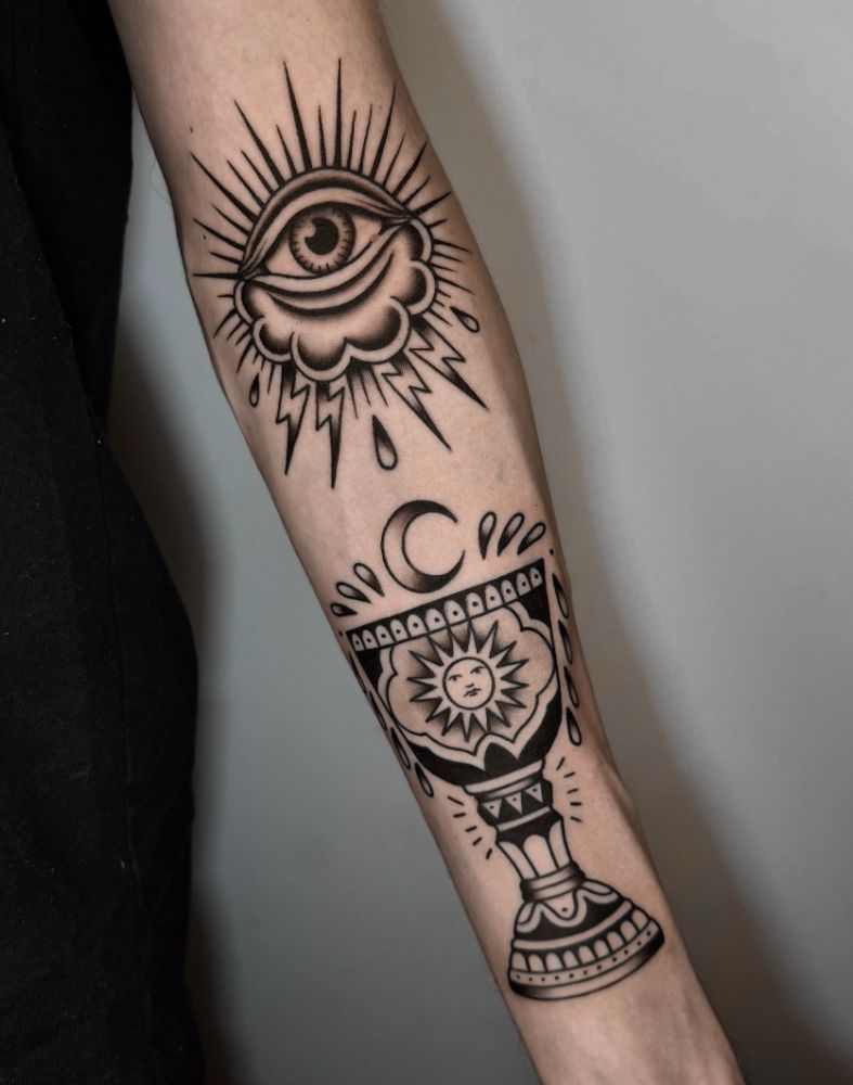 Tatuagem de olho sobre nuvem e cálice com sol, no antebraço.