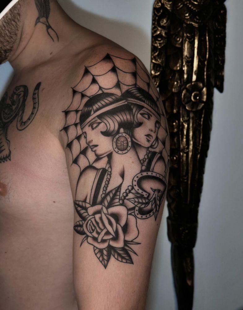 Tatuagem de mulher com teia de aranha e rosa, no ombro.