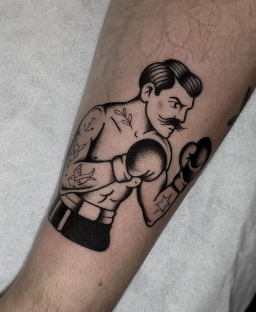 Tatuagem de boxeador de bigode em guarda, no antebraço.