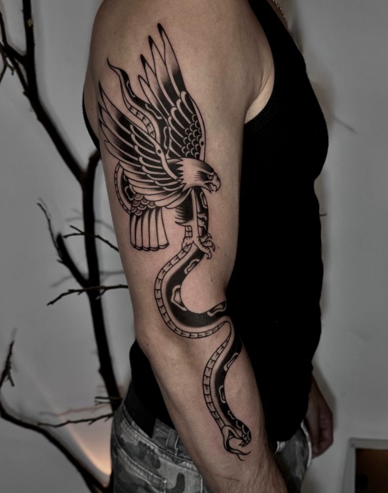 Tatuagem de águia segurando uma serpente, no braço.