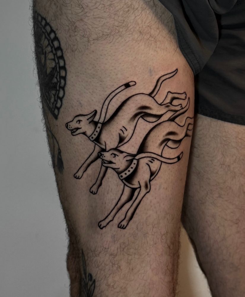 Tatuagem de dois cachorros correndo, na coxa.