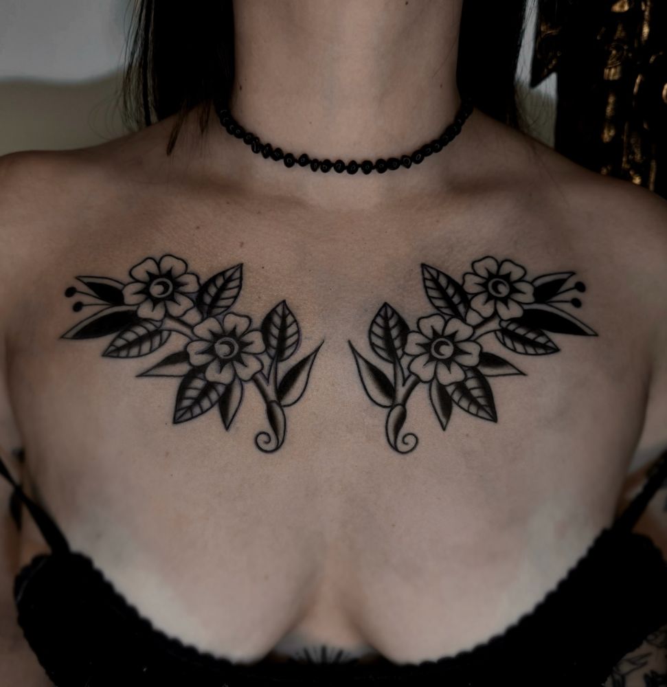 Tatuagem simétrica de flores old school no peito.