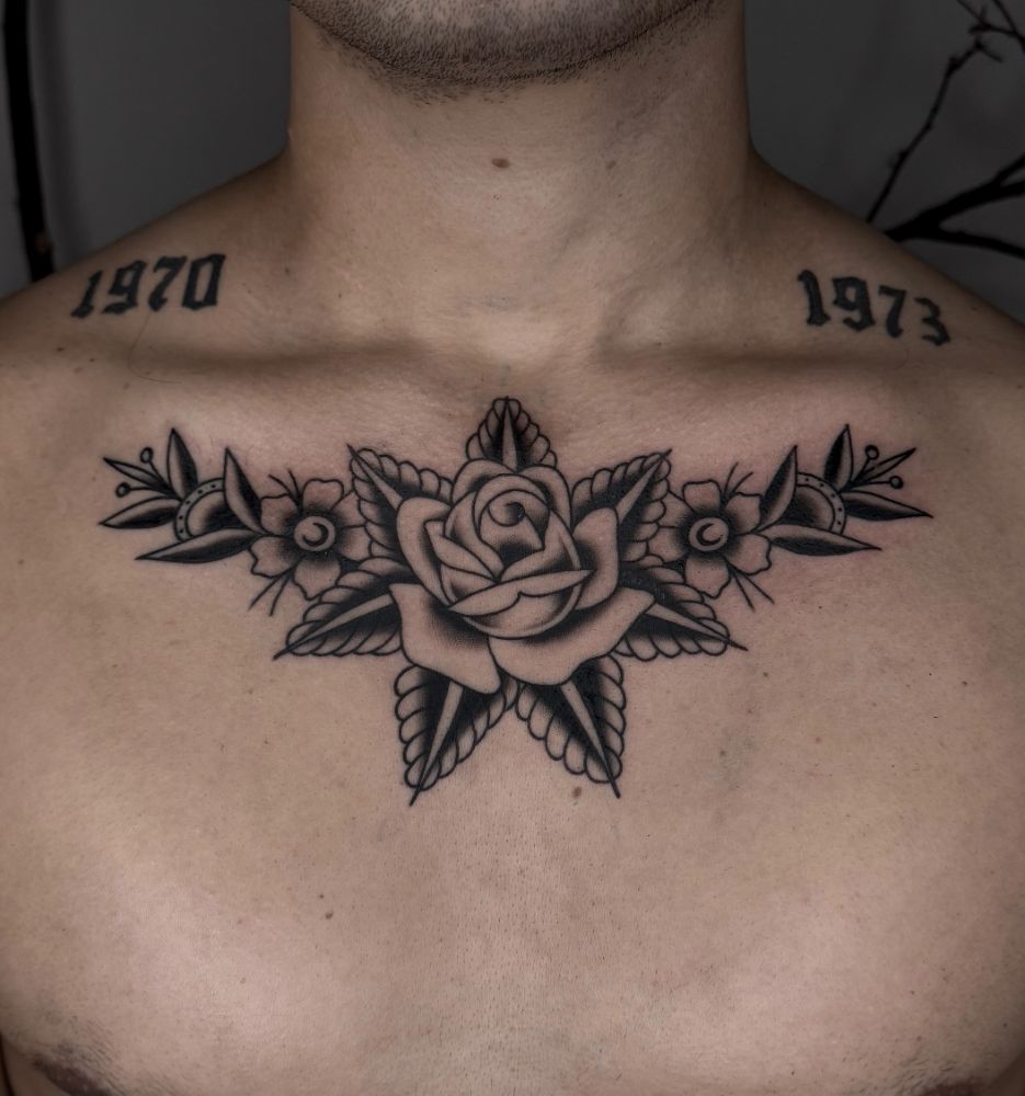 Tatuagem de rosa e flores atravessando o peito.