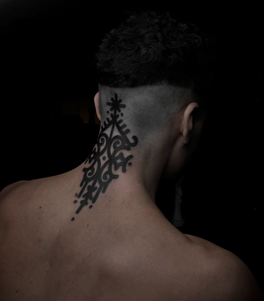Tatuagem ornamental em preto sólido, na nuca.