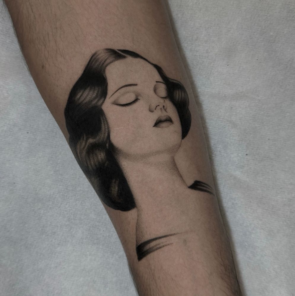 Tatuagem do rosto de uma mulher de olhos fechados, na perna.