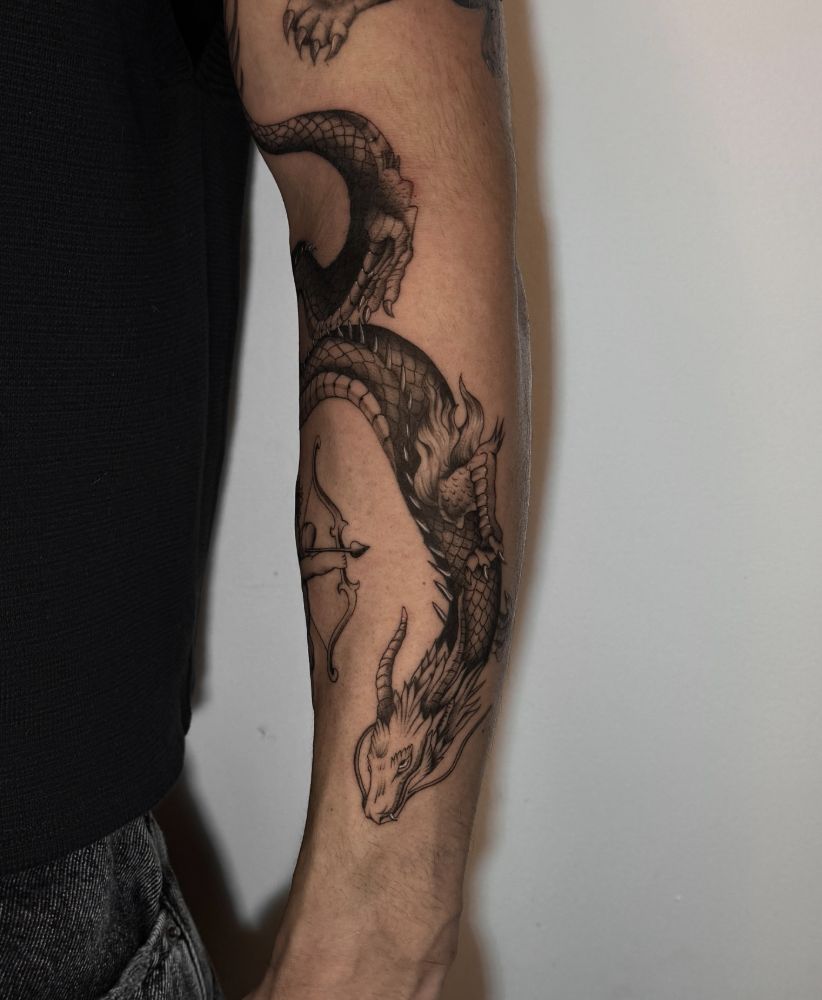 Tatuagem de dragão descendo pelo antebraço.