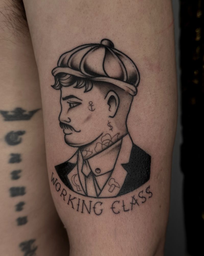 Tatuagem de retrato masculino com a frase Working Class, no braço.