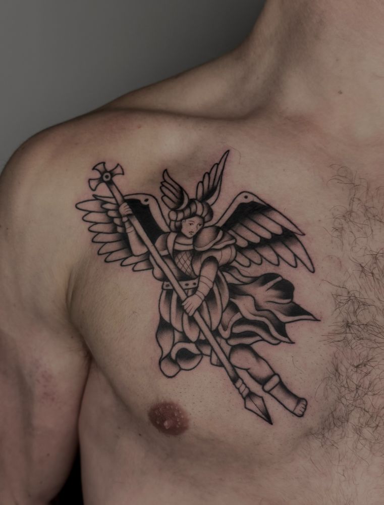 Tatuagem de arcanjo com estandarte, no peito.