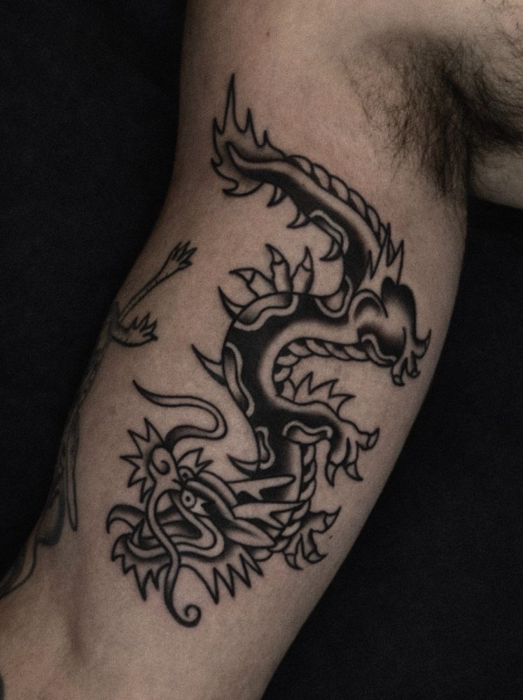 Tatuagem old school de dragão, no braço.